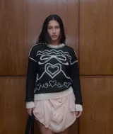 Buzo de cuello redondo con calce holgado, confeccionado en tejido de punto grueso con diseño jacquard de moña y corazones en contraste.