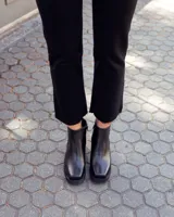 Botinetas de cuero negro con plataforma y taco cuadrado. Presentan un diseño combinado con una textura tipo reptil en la parte posterior y cierre lateral.