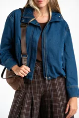 Campera bomber de jean azul con cierre frontal metálico, cuello alto y diseño oversize. Presenta costuras reforzadas y puños rectos.