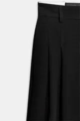 Pantalón de tiro medio color marrón, con pinzas en el delantero, perneras anchas de corte recto y trabillas para cinturón. Cuenta con bolsillos laterales y traseros, y cierre frontal con cremallera y botón.