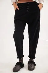 Pantalón de pana de algodón con tiro bajo y calce relajado. Presenta una botonadura frontal visible como detalle principal y diseño de estilo vintage.