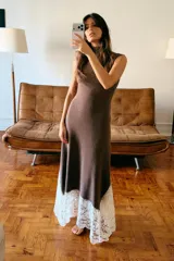 Vestido largo de cuello perkins y diseño sin mangas, confeccionado en tejido de punto color marrón. Presenta un bajo con corte evasé y detalle de encaje en color crudo a contraste. Cierre posterior con cremallera oculta.