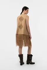 Chaleco de efecto gamuzado color beige, con detalles tejidos al crochet en forma de rombos, flecos largos en el ruedo y diseño sin mangas.