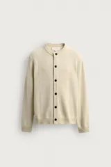 Cardigan de punto en hilatura de algodón y lino, con ajuste regular, cuello redondo, manga larga y acabados en rib. Presenta cierre frontal de botonadura con botones oscuros.