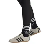 Championes Adidas modelo Tokyo, de diseño retro y perfil bajo. Confeccionados en gamuza color beige con las icónicas tres tiras laterales en cuero negro, forro interno de cuero y suela de caucho color caramelo.