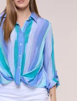 Blusa de gasa blanca con estampado floral multicolor, cuello con solapa, cierre frontal de botones y diseño anudado en la parte delantera.