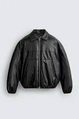 Cazadora acolchada relaxed fit de efecto piel en color negro, con cuello camisero, cierre frontal de cremallera metálica, bolsillos frontales de vivo y puños elásticos.