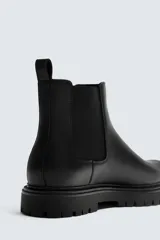 Bota tipo Chelsea de cuero color marrón oscuro, con paneles elásticos laterales, tirador trasero y suela track con volumen.