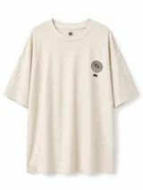 Remera oversize color beige, con cuello redondo y diseño gráfico pequeño en el pecho.