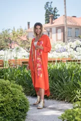Vestido tipo camisola largo de color naranja, con mangas largas, diseño abotonado al frente y detalles de arte abstracto pintado a mano en tonos dorados, cobre, turquesa y celeste.
