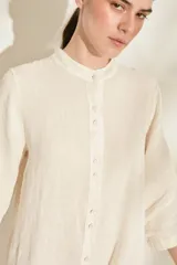 Túnica midi marrón de lino, con cuello mao, cierre frontal con botones y bolsillos laterales.