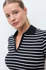 Remera de tejido canalé a rayas horizontales blancas y negras, con cuello polo y escote en V sin botones, de manga corta y corte ajustado.