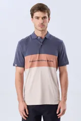 Remera polo de manga corta con diseño en bloques de color en tonos azul marino, blanco y verde militar, con bordado frontal y cierre de botones.