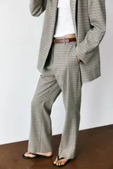 Pantalón de tiro alto color negro, de corte recto y pinzas frontales. Incluye un cinturón delgado de cuero marrón con hebilla metálica dorada.