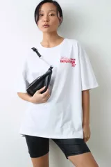 Remera de algodón gris melange con corte oversize, manga corta y estampa localizada en el frente con motivos deportivos en tonos verde y rosado.