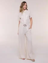 Conjunto de dos piezas confeccionado en lino, de estilo casual safari. Incluye camisa de manga corta con cuello camisero con bordado festoneado, abotonadura frontal y bolsillos en el pecho; y pantalón palazzo de tiro alto con bolsillos y cinturón con hebilla metálica dorada.