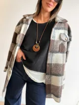 Sobrecamisa de paño con diseño a cuadros en tonos marrones, grises y blancos. Presenta cuello clásico, cierre frontal con botones y bolsillos delanteros con tapa.