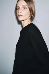 Jersey de punto liso color verde, con cuello redondo y manga larga. Confeccionado en lana suave.