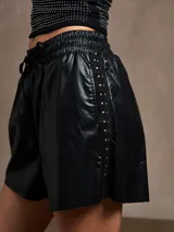 Short negro de cuero sintético con cintura elástica y cordón ajustable.