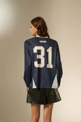 Remera de manga larga estilo deportivo, confeccionada en tejido técnico. Presenta un diseño color block en tonos bordó y rosa, con cuello mao y estampado gráfico frontal en color blanco.