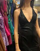 Vestido largo sin mangas con escote en V halter y aberturas laterales (cut-outs) en la cintura. El cuerpo superior presenta un llamativo diseño estampado multicolor, mientras que la falda larga es de tejido texturizado brillante en color verde esmeralda con inserciones godet en el ruedo.
