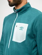 Buzo de entrenamiento Umbro con medio cierre frontal, cuello alto y bolsillo en el pecho de nylon con cierre. Presenta una textura sutil en el tejido y logo de la marca estampado en el bolsillo.