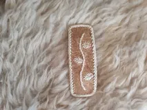 Broche para pelo artesanal de cuero con bordados en tiento fino.