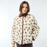 Chaqueta de sherpa color crema con estampado floral en tonos marrones, amarillos y verdes. Tiene cuello camisero y ribete de pana marrón.