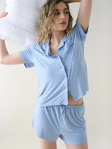 Camisa de dormir de manga corta color celeste en viscosa suave y liviana, con botones frontales, cuello con solapas, bolsillo en el pecho y detalles de ribetes a tono.