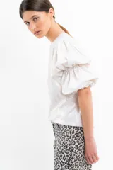 Remera blanca brillante con mangas abullonadas y puños elásticos.