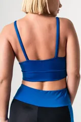 Top deportivo de color azul francia, con escote redondo, breteles finos ajustables y detalle de aros metálicos en la unión de los breteles con el frente. Presenta una faja ancha de doble tela en la base para mayor soporte.
