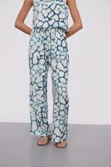 Pantalón largo de viscosa con estampado abstracto en tonos azules y blancos, cintura alta con cordón ajustable y corte ancho.