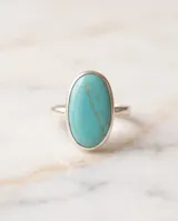 Anillo de plata 925 con una gran piedra natural turquesa de forma ovalada en el centro.