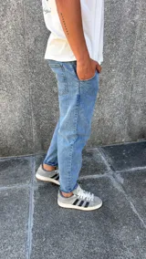 Pantalón de jean estilo slouchy, de corte holgado en la parte superior y ligeramente ajustado hacia los tobillos, con ruedo doblado.
