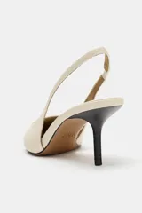 Zapato destalonado de tacón medio fino y acabado en punta, en color crudo, con tira trasera elástica.