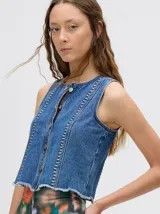 Chaleco de denim liviano con cierre frontal de botones metálicos, detalle de apliques metálicos verticales y ruedo con terminación desflecada.