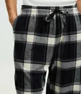 Pantalón de pijama de corte recto confeccionado en franela de algodón con estampado de cuadros en tonos blanco y negro. Presenta cintura elástica con cordón de ajuste para mayor comodidad.
