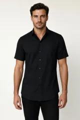 Camisa negra de manga corta, con cuello clásico, cierre frontal con botones y bolsillo ojal en el pecho.