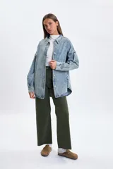 Sobrecamisa de jean en tono celeste con efecto lavado, corte oversize, cuello clásico, cierre frontal con botones metálicos y mangas largas con detalle de frunces en los hombros.