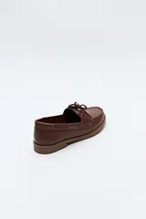 Zapato náutico de cuero sintético color marrón, con cordones decorativos, costuras a la vista y suela de goma antideslizante.