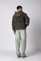 Buzo canguro de corte oversize en color gris con efecto lavado desgastado. Presenta diseño con recortes horizontales, capucha amplia y puños acanalados con etiqueta de marca en la manga.