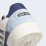 Championes Adidas Drop Step Low 2.0 de estilo urbano, con diseño de corte bajo. Presenta una combinación de colores blanco, azul claro y azul marino, con paneles de ante y piel sintética. Incluye el logo de Adidas en el lateral y en la lengüeta, con suela de goma esculpida.
