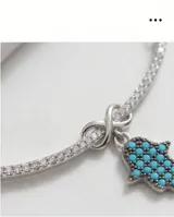 Collar de plata 925 con cadena fina, diseño de barra central con circonias y dije colgante en forma de mano Hamsa con incrustaciones de piedras turquesas.