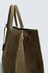 Bolso tipo bandolera de piel con acabado abatanado, diseño rectangular con doble asa de mano y detalle de llavero colgante. Cuenta con compartimento principal con cierre de mosquetón y bolsillo interior con cremallera.