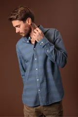 Camisa de hombre celeste con estampado de rayas horizontales en tonos azules y grises, de manga larga y cuello abotonado.