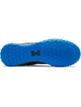 Championes de fútbol Under Armour Shadow Turf 3, diseñados para césped artificial. Presentan una parte superior sintética gris con detalles en azul, entresuela Charged Cushioning para amortiguación y suela de goma con tacos estratégicos para máximo agarre.