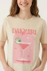 Remera de algodón color beige, de manga corta y corte clásico, con estampa frontal ilustrada de un trago Daiquiri y la inscripción en letras rosadas.