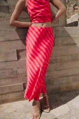 Falda midi fluida confeccionada en tejido satinado con estampado de rayas diagonales en tonos rojo y rosado, y cintura elástica.