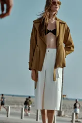 Chaqueta estilo trench corta color azul marino confeccionada con lino. Cuenta con cuello solapa, manga larga con trabilla, bolsillos delanteros de vivo y cierre frontal con lazada ajustable en la cintura.