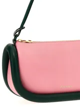 Bolso de hombro JW Anderson modelo Bumper-15, color rosa con ribetes tubulares acolchados en verde oscuro. Tiene correa de hombro ajustable, cierre con cremallera superior y logo estampado en el frente.